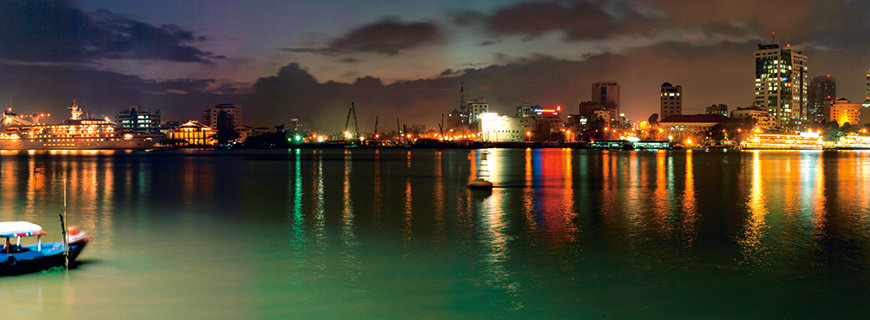 Internationale Karriere in Vietnam ein Hafen mit kleinen Booten, im Hintergrund das Leuchten der Stadt