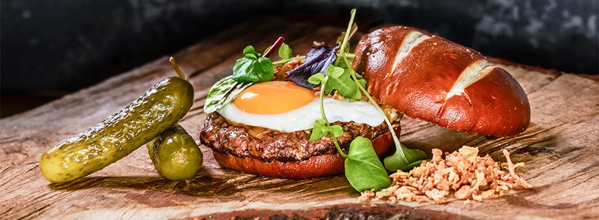 Burger mit Laugenbun, Gewürzgurke, Spiegelei und Fleischpatty im C’s Authentic Food in Koblenz 