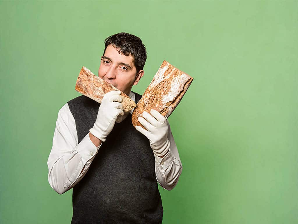 andreas djordjevic mit laib brot in den händen. von einem beißt er ab