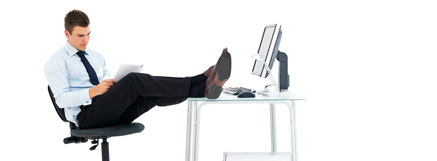 ein Herr im Büro, die Beine verschränkt auf den Tisch gelegt 