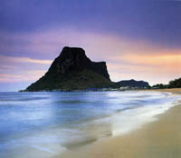 ein Sandstrand und türkisblaues Meer, ein Berg und ein rosa-blauer Himmel in der Dämmerung
