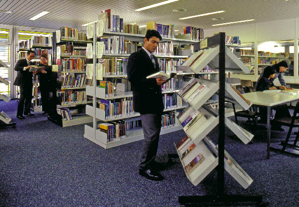 Ein mann steht in einer bücherein und durchblättert stehend ein buch