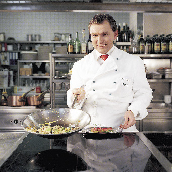 Toni Mörwald mit einer Pfanne in der Hand in der Küche 
