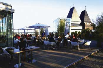 ein großfläche Gastterrasse gegenüber von einem Kirchenturm 
