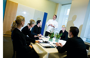 ein Gruppenmeeting, der Koch redet, der Rest sitzt und lauscht 