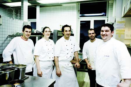Marco Pedrelli und sein Team gekleidet in weiss und in der Kueche stehend 