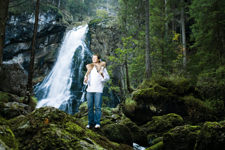 Andreas Döllerer mit einem Reh um den Hals vor einem Wasserfall 