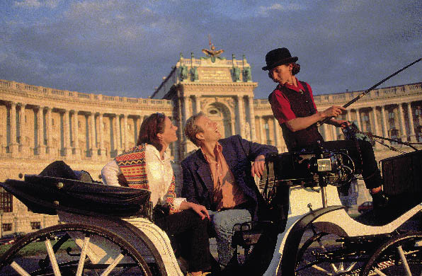 eine Frau und ein mann in einer pferdekutsche vor der hofburg in wien 