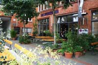 ein uriges aus rotem ziegelstein und hinter grünen büschen verstecktes restaurant mit einem schanigarten