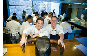 zwei Mitarbeiter des elBulli mit dem Stierkopf, ihre Haende an dessen Hoernern 