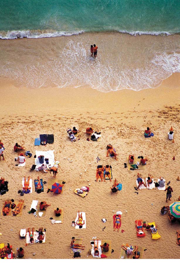 Sandstrand mit Menschen die sich sonnen und einem liebespaar im wasser 