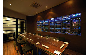 Saint Pierre Restaurant mit einer Vinothek aus Glas hinter einer langen Tafel 