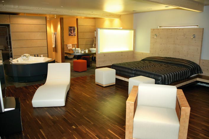 ein großes und offenes Hotelzimmer mit einem Kingsizebett und einer Whirlpool Badewanne 