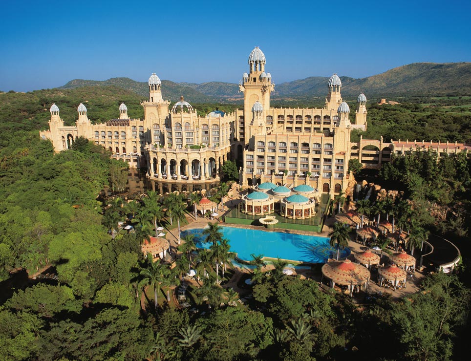 ein enormer Hotelkomplex inmitten einer grünen Berglandschaft mit Swimming Pool und großen Fenstern 