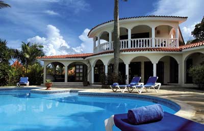 der Pool inklusive Sonnenliegen und das Poolhaus des Hotels sind sichtbar 