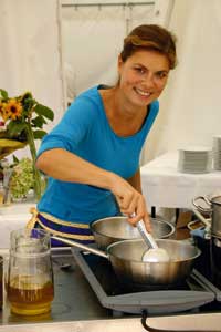 Sarah Wiener beim kochen in einem blauen Tshirt 