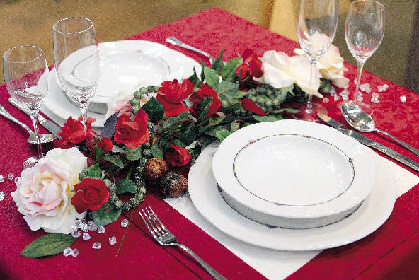 Herbstlich inspiriertes blumenarrangement schmückt einen in dunklem Rot gedeckten tisch 