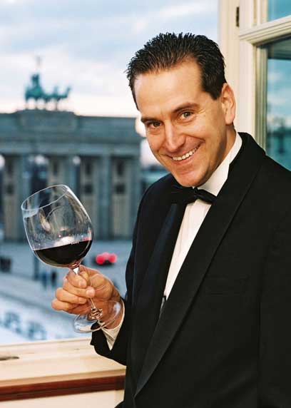 Gerhard Retter im Anzug mit einem Glas Rotwein in der Hand 