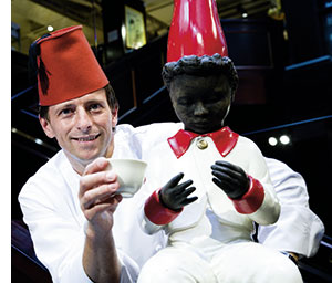 ein Superkoch mit hoher roter Kochmütze und einer schwarzen Meinl Puppe 