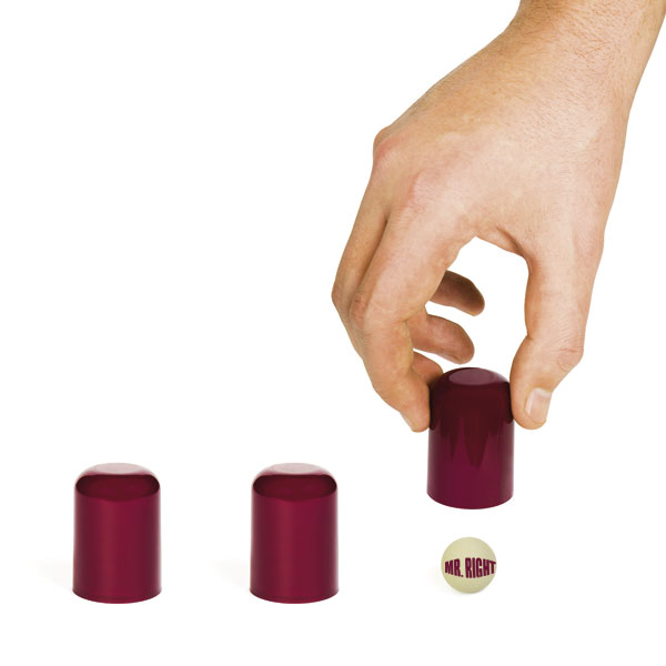 eine Hand findet die Kugen beim Becherspiel
