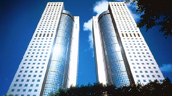 ein Hochhaus mit Doppeltürmen primär aus Glas, aus der Froschperspektive 
