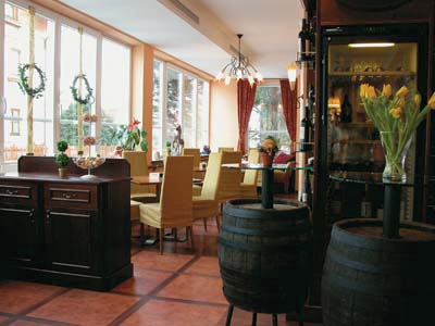 ein mit esstischen eingerichteter raum, als tisch für blumen und eine lampe dienen weinfässer