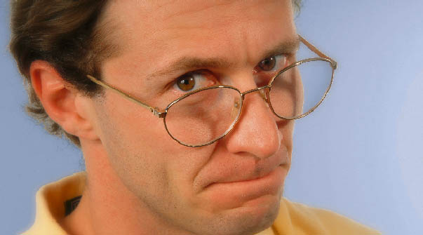 ein Mann mit einer Lesebrille sieht skeptisch in die Kamera 