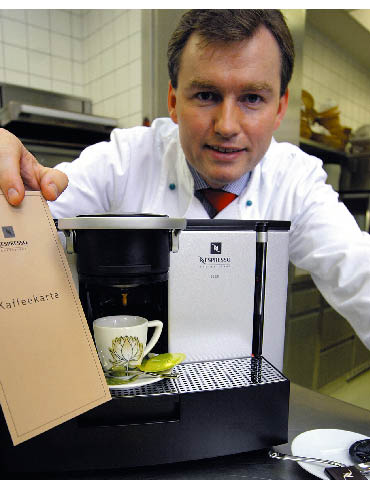 Ein Mann steht hinter einer Espressomaschine während diese Kaffee herunter lässt 