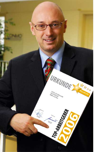 Jürgen Pichler Herr Jürgen Pichler steht im Anzug und hält die Urkunde des Top Arbeitgebers 2006 vor der Brust