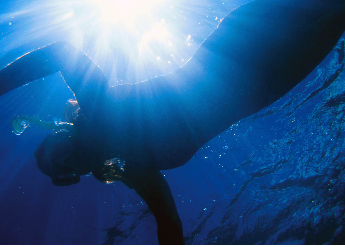 Unterwasser eine Frau schnorchelnd unter Wasser während die Sonne im Wasser reflektiert