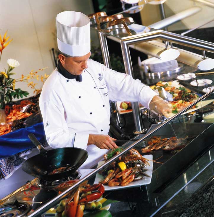 Ein Koch steht hinter einem Buffet mit diversen Köstlichkeiten 