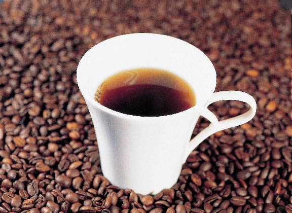 Kaffeeduell eine weiße Tasse gefüllt mit Kaffee plaziert auf Kaffeebohnen