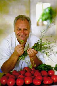 Eckart Witzigmann mit Kräutern in der Hand und vor ihm liegt eine Kiste Tomaten 