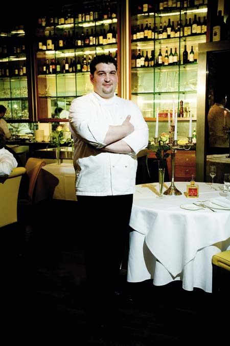 Starkoch Marco Pedrelli steht mit verschraenkten Armen in seinem Restaurant 