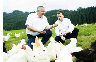 Gerhard Fuchs auf einer wiese mit hennen und einem kollegen 