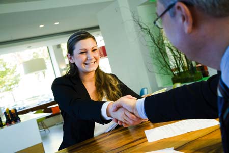 Eine Frau und ein Herr sitzen gegenüber voneinander und geben sich die Hand 