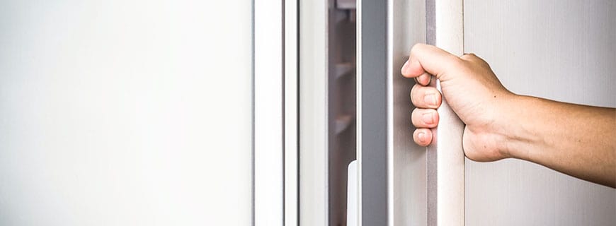 eine Hand greift an den Kühlschrank