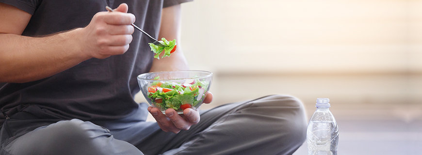 Mann isst eine Schüssel Salat