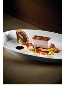 Schweinebauch mit Erdäpfel-Blunzen-Roulade und Kümmeljus auf Tomatenkraut