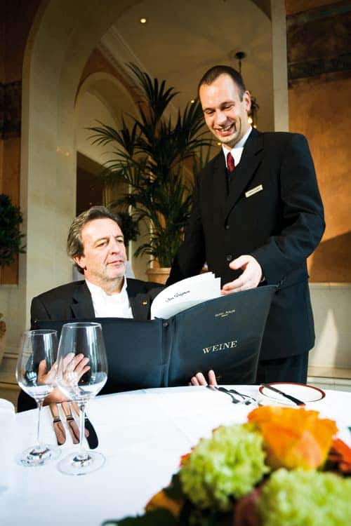Gast mit der Weinkarte, während der Sommelier ihn beratet