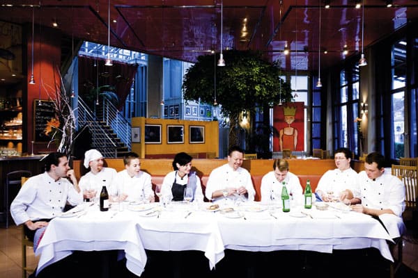Alexander Tschebul auf einer langen Tafel sitzend mit seinem Team 