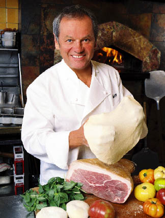 Wolfgang Puck mit Prosciutto und gemüse während er einen Teig ausbreitet