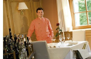 Didi Dorner in orange-farbenem Kochgewand im Restaurant stehend 