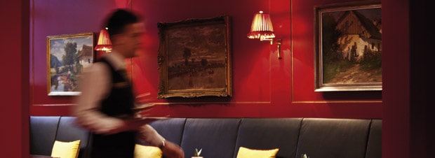 Prager Restaurant tiefrote Wände, blauer Pölstermöbel, der Kellner in Bewegung, ein Restaurant in Prag