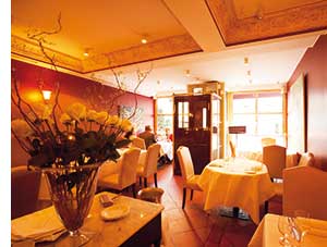ein Restaurant, vorne links im Bild eine grosse Vase mit gelben Rosen 