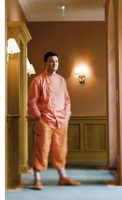Didi Dorner in orange gekleidet im Hotelflur stehend 