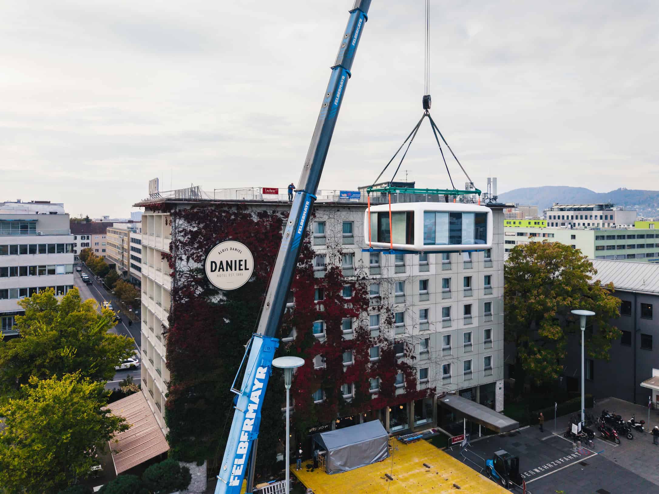 Blick von oben auf das Hotel Daniel Graz, während ein Kran den LoftCube auf das Dach hebt.