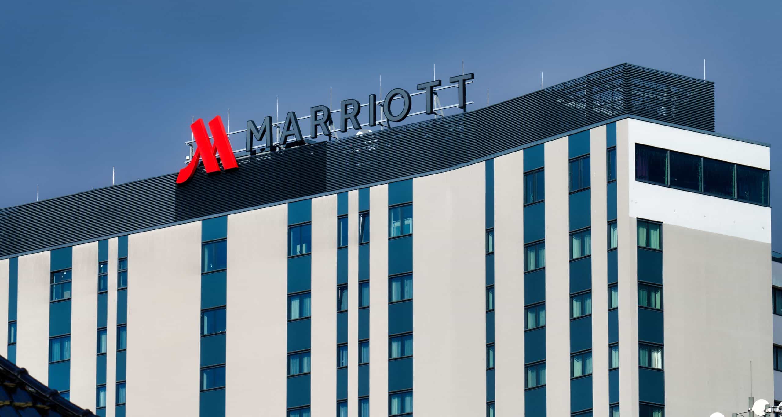 Außenansicht eines Marriott-Hotels mit weißer Fassade, blauen Fensterelementen und großem Marriott-Schriftzug auf dem Dach.