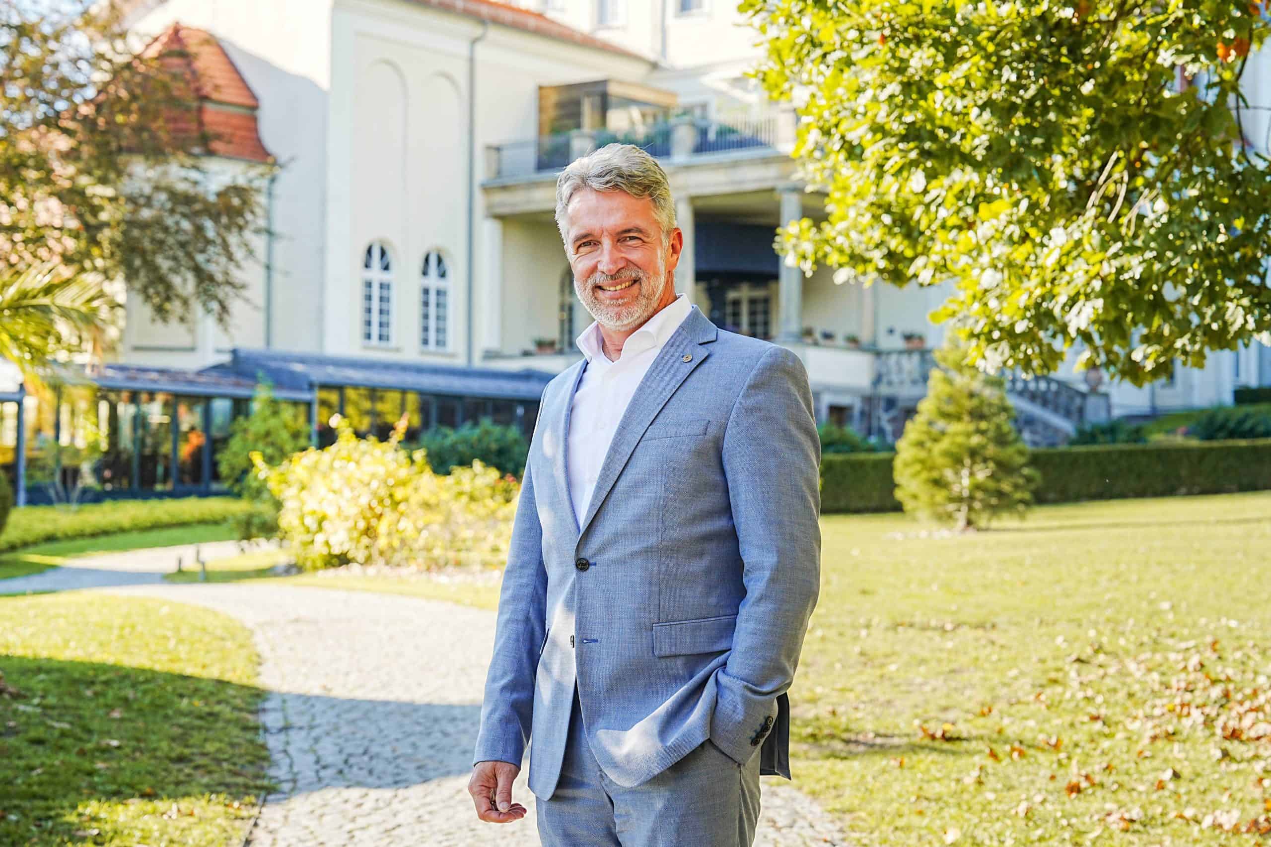 Carsten Willenbockel in grauem Anzug vor dem Schloss Fleesensee