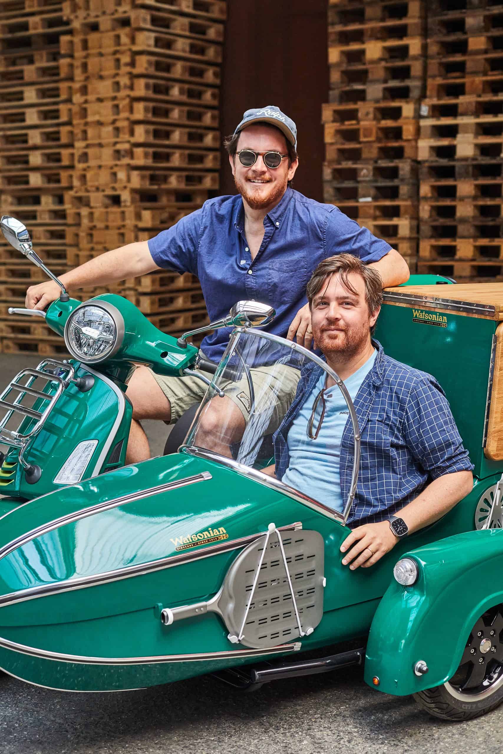 Pizza-Pilgrims-Gründer Thom und James Elliot auf einem grünen Motorroller mit Beiwagen.